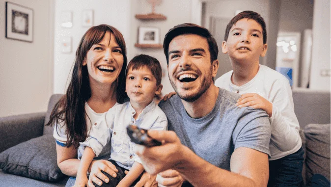 {Família feliz assistindo televisão|Pais e filhos assistem juntos na sala|Cena familiar curtindo FullTV|Ambiente doméstico com TV digital ligada}